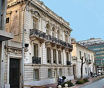 Façade d'un grand bâtiment blanc percé de fenêtres.