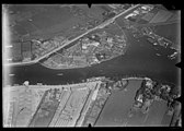 De Omval tussen de Amstel en de Weesperzijde. Links vooraan de Remise Watertoren van de Gemeentetram Amsterdam, voorloper van de Remise Lekstraat, met de oude watertoren van de gemeente Nieuwer-Amstel. Aan de overkant Bertels Oliefabrieken; circa 1920. Luchtvaartafdeeling, 1920-1940.