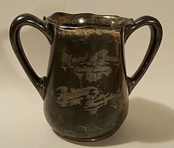 A tarnished, metal, double-handled cup. An inscription, in script, reads: "Univ of Penna/Relay Races/1895/Harvard vs. Pennsylvania."