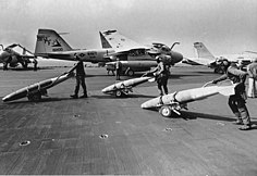 An A-6E TRAM Intruder (NF-506) from VA-115 and an F/A-18A Hornet (NF-106) from VFA-195 taxi to a catapult during the Gulf War.