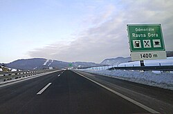 Motorway approaching the Ravna Gora rest area; a directional traffic sign specifying some rest area amenities is visible on the right side of the road.