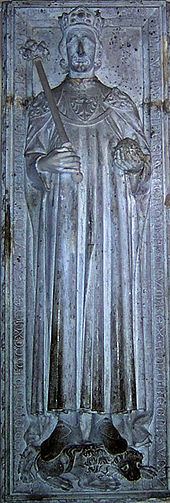 Fotografie náhrobní desky s reliéfem ležícího muže v královském rouchu s římskou korunou na hlavě a královským žezlem a jablkem
