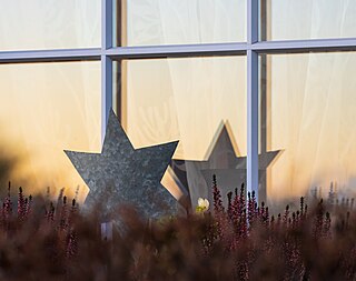 Christmas star decoration at a window with the reflection of a sunset