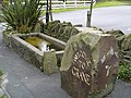 An old horse trough and a welcome sign at the junction with Grane Road.