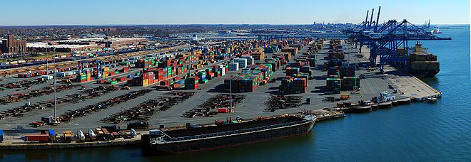 Vue de haut du port et des docks, on observe le stockage de nombreux conteneurs et l’acheminement de marchandises par train.