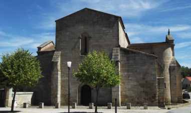 Photographie d'un parvis d'église romane ombragé de petits arbres.