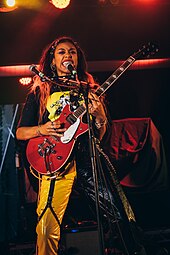 A picture of a female group with guitars performing on stage.