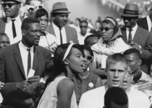 A crowd, mostly made up of black men in suits and black women in dressed up attire