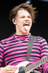 A picture of a man performing with an electric guitar on stage.