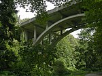 An art deco styled concrete bridge over a wooded ravine