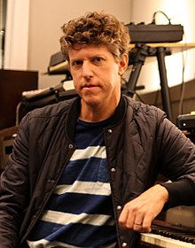 Greg Kurstin mengenakan kaus loreng dengan jaket.