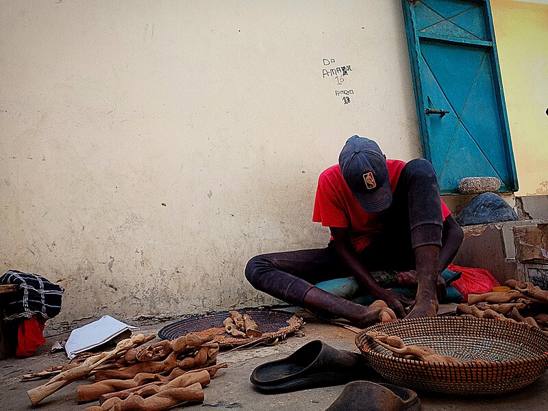 File:African kid carving women shaped statuettes.jpg