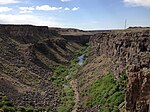 A small stream flowing through an arid, steep-sided canyon