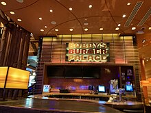 A small indoor restaurant building with a large logo and several lights above.