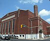 View of Jersey City Armory, a Beaux-Arts style building in redbrick with terra cotta trim, tall windows on one side topped with a stone strip carved with the words "New Jersey National Guard"