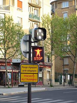 Feu rouge dont le mot "Stop" clignote signalant aux piétons de ne pas traverser la voie de tramway.