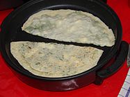 The filled and sealed pastries being cooked over a sac griddle until they become golden brown.