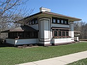 Two story Stockman House oblique street view from the northwest. An enclosed veranda is at left and part of the entrance is visible at far right.