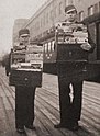 Two boys standing next to each other holding display cases of magazines on a railway platform. Rautavaara is the taller boy on the right.