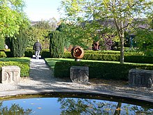 Photographie en couleur de blocs portant des lettres au milieu d'un jardin.