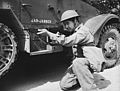 A valued Chinese member of a halftrac armored car crew at Fort Knox, Kentucky, learns the art of making it hot for the Axis in any battle situation