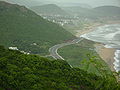 Aerial view of two-lane highway, surrounded by forest and beach]]