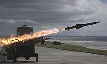 Photograph of a missile in the process of launching in the night.