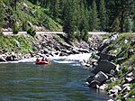 Rafters floating down a small river surrounded by forest