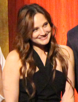 A 31-year-old woman with brown hair smiling to the right of the camera.
