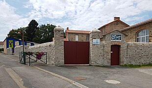 Photographie en couleurs d'un ensemble de bâtiments avec une cour close d'un mur portant la mention « Ecole Saint Joseph ».