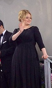 Adele mengenakan sebuah gaun hitam.
