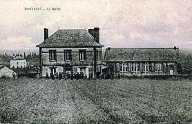 Carte postale noir et blanc représentant deux bâtiments en arrière-plan et un champ au premier plan.