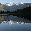 Two snow-capped mountains reflect in a lake