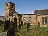 A stone church seen from a slight angle, with a flat-topped tower at the left, then the ruined south wall of the nave, and on the right part of the chancel