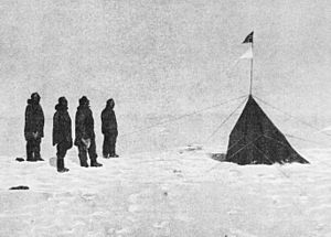 In an icebound landscape four figures stand, left, facing a small pointed tent from which two triangular flags are flying.