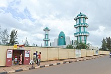 Photograph of the mosque from the street, with a small local shop visible in the foreground