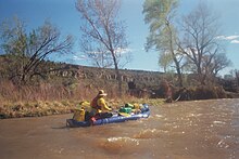 A single person paddles an inflatable loaded with about twice his own body volume in goods, neatly stacked and lashed fore and aft to a height of over 50cm.