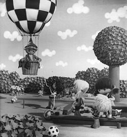 Sandmännchen letí v horkovzdušném balónu. Obrázek u příležitosti 25. výročí televizního pořadu.