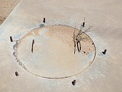 A close-up view of the first calibration target manhole, with cement cover and rebar handles. Around the cover protrude six equidistant pieces of rebar.