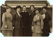 Photographie d'un groupe de six femmes à l'extérieur d'un bâtiment