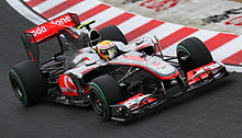 A silver-and-red single-seater racing car is driven around a tarmac course.