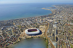 'n Lugfoto van Gqeberha met die Nelson Mandelabaaistadion, 'n bekende baken, in die voorgrond.