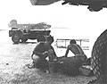 US Navy maintenance crews VB-106 clean engine parts under an airplane wing while raining at Momote Airfiled in March 1944 at Manus Naval Base