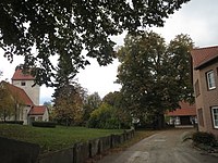 Blick von Osten entlang der Alten Dorfstraße, links die Dorfkirche, geradezu am Südrand der Straße der erste der beiden Bäume