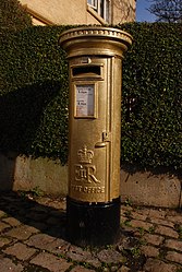 Gold pillar box outside the White Lion public house, Disley, Cheshire.