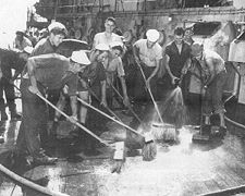 Sailors scrubbing down a ship deck.