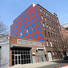 a one story building next to a seven story building which has a large mural across it's side