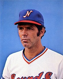 A portrait of a man in a blue cap with a white "N" on the front and a white baseball jersey with "Sounds" across the chest in red and blue