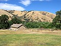 View of the barracks from the front porch of the commanding officer's quarters. The split rail fence at the near end of the barracks denotes the foundation outline of another barracks yet to be reconstructed.