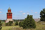 Klockstapel med kyrkan i bakgrunden